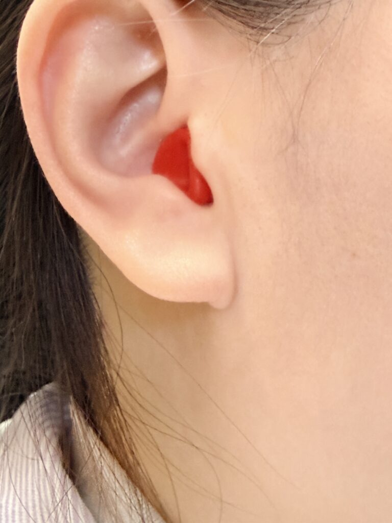 女性佩戴紅色睡眠耳塞，舒適貼合耳道